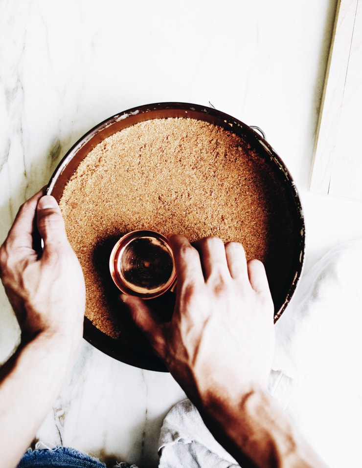 Pressing graham cracker crumbs into cheesecake pan